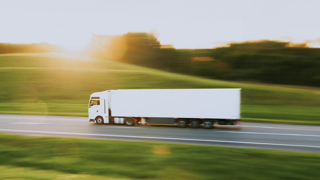 A white articulated lorry on a country road in low evening light